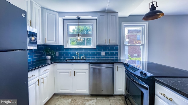 kitchen featuring appliances with stainless steel finishes, pendant lighting, white cabinets, and sink