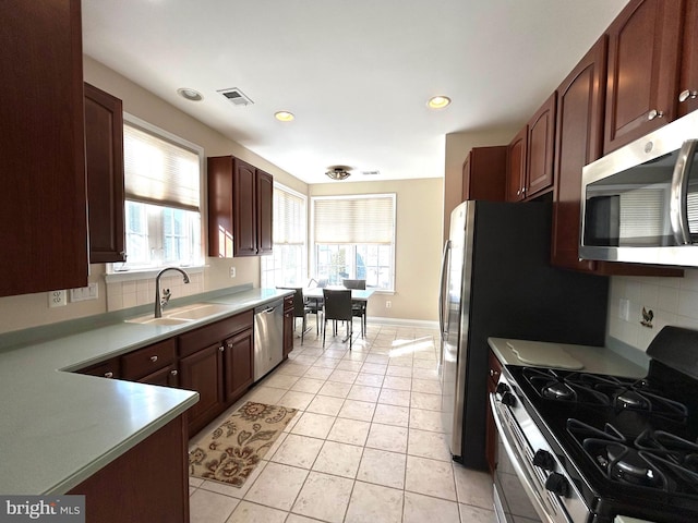 kitchen featuring light tile patterned flooring, appliances with stainless steel finishes, sink, and backsplash