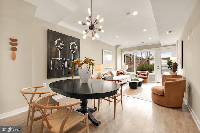 dining room featuring light wood-type flooring, ornamental molding, and an inviting chandelier