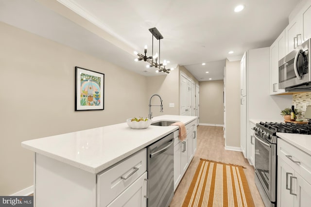 kitchen featuring decorative light fixtures, sink, white cabinetry, a center island with sink, and stainless steel appliances