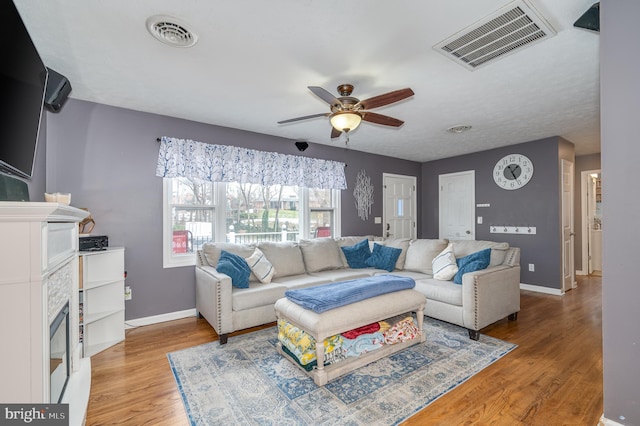 living room featuring ceiling fan, hardwood / wood-style floors, and a fireplace