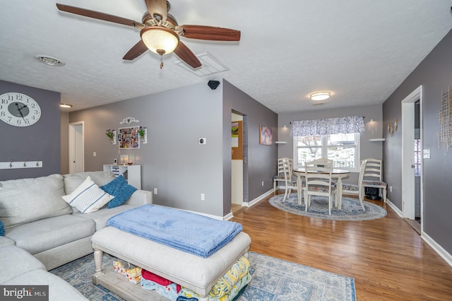 living room with ceiling fan, a textured ceiling, and hardwood / wood-style floors