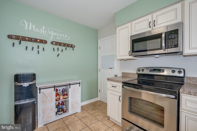 kitchen featuring light tile patterned floors, appliances with stainless steel finishes, and white cabinetry