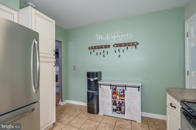 kitchen featuring light tile patterned floors, black / electric stove, white cabinetry, and stainless steel refrigerator