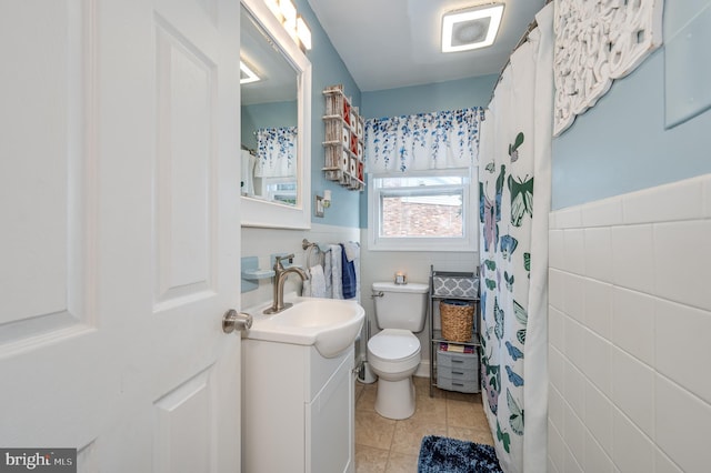 bathroom with toilet, tile patterned flooring, tile walls, and vanity