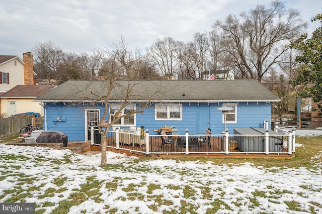 snow covered back of property with a deck