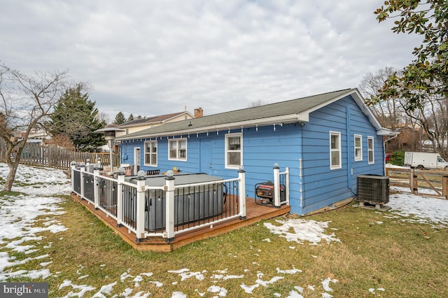 snow covered back of property featuring a deck, a lawn, and central air condition unit