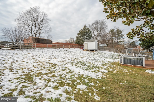 snowy yard with a deck and a storage unit