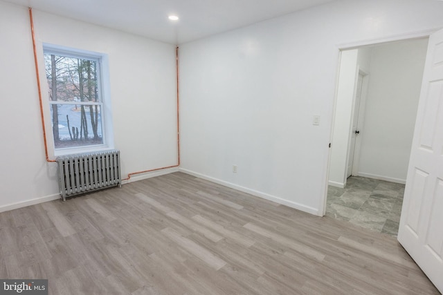 unfurnished room featuring radiator and light wood-type flooring