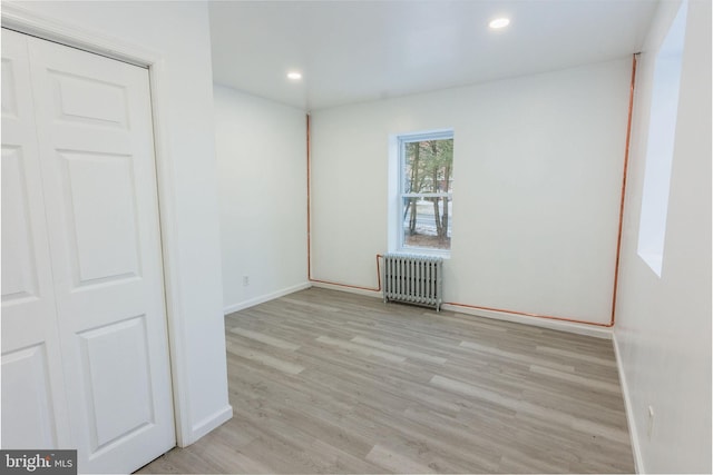 spare room with radiator heating unit and light hardwood / wood-style flooring