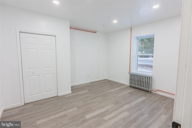 spare room featuring radiator and light wood-type flooring