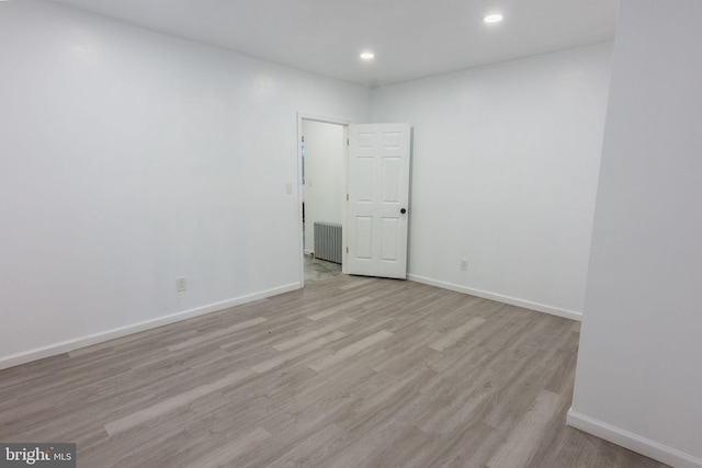 empty room featuring radiator and light hardwood / wood-style floors