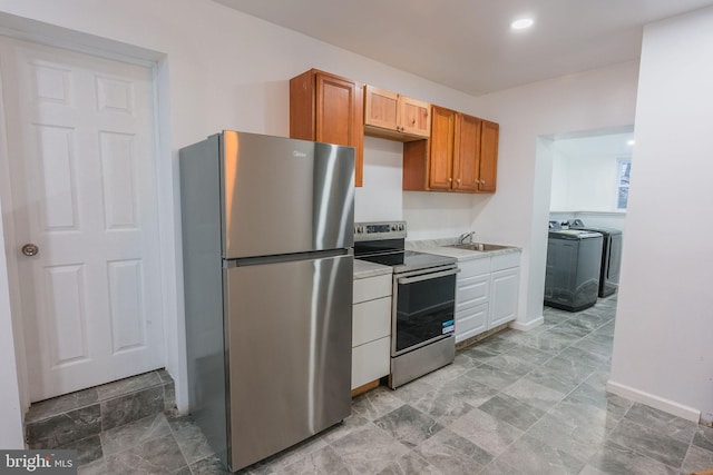 kitchen with washer / dryer, appliances with stainless steel finishes, and sink