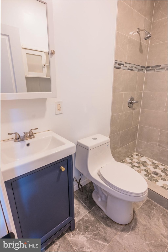 bathroom featuring tiled shower, vanity, and toilet