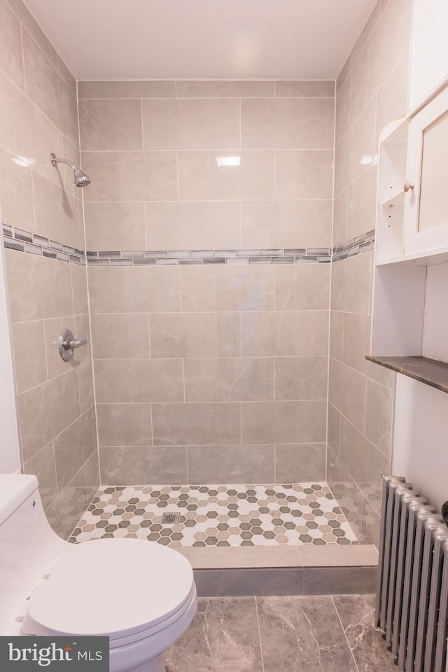 bathroom featuring radiator, a tile shower, and toilet