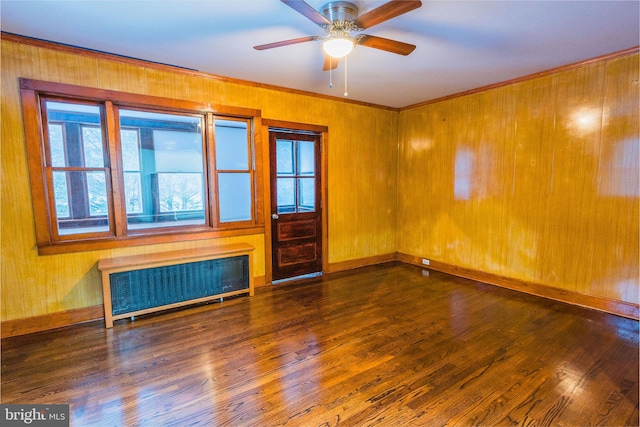 empty room featuring ornamental molding, radiator heating unit, ceiling fan, and dark hardwood / wood-style flooring