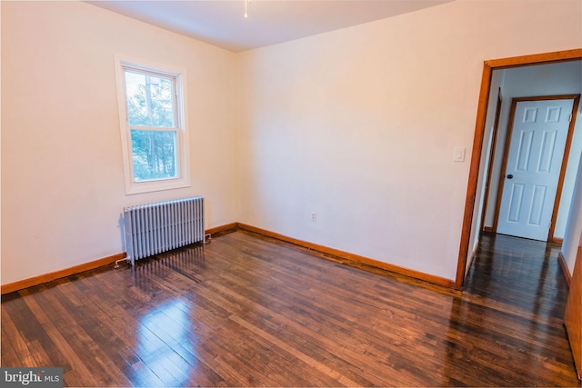 spare room with radiator heating unit and dark hardwood / wood-style floors