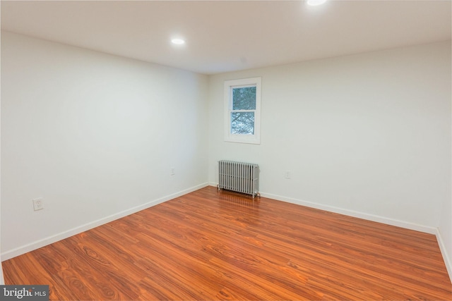 empty room featuring wood-type flooring and radiator