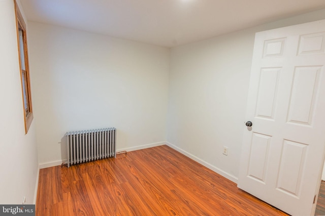 empty room featuring hardwood / wood-style flooring and radiator heating unit