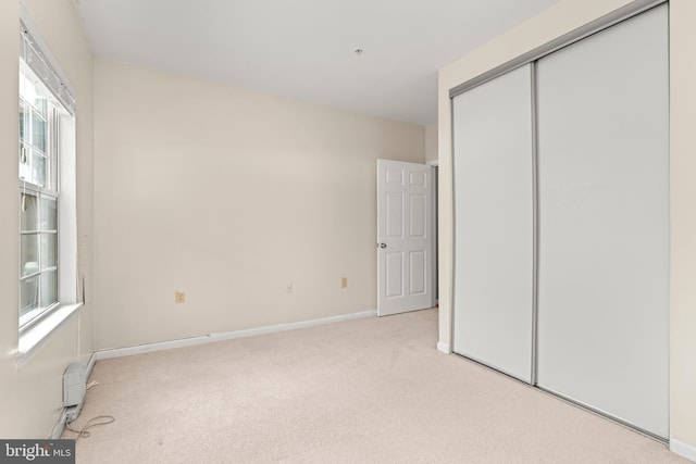 unfurnished bedroom with light colored carpet, multiple windows, and a closet