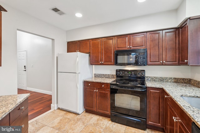 kitchen featuring light stone counters, light tile patterned flooring, and black appliances