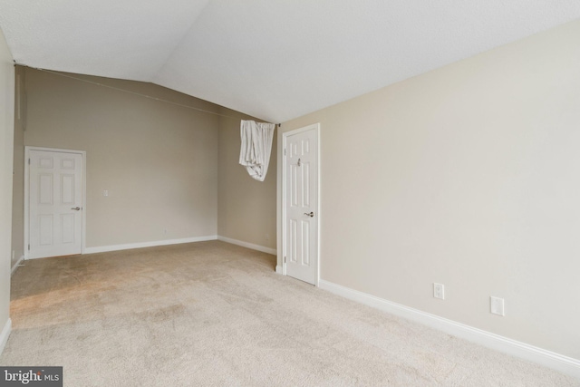 spare room featuring light carpet and vaulted ceiling