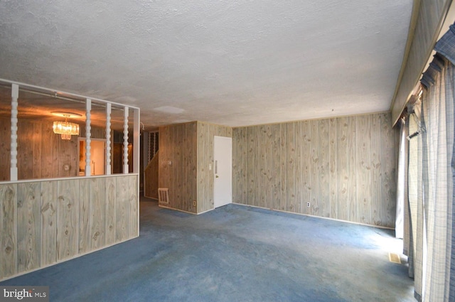 basement featuring a notable chandelier, a textured ceiling, and dark colored carpet