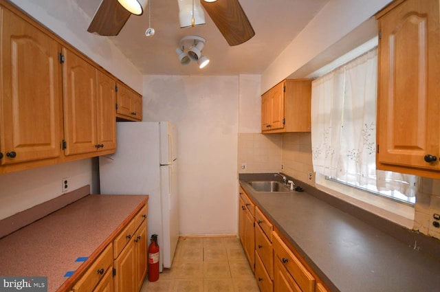 kitchen featuring ceiling fan, sink, white fridge, and backsplash