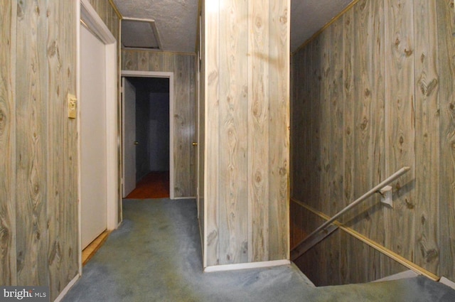 hall featuring wooden walls and dark colored carpet