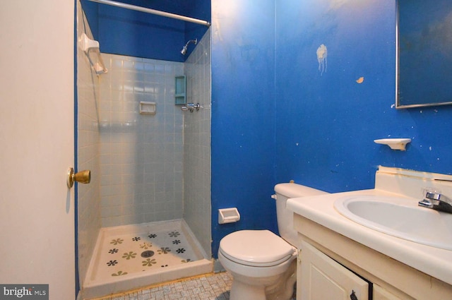 bathroom featuring vanity, toilet, tile patterned flooring, and a tile shower