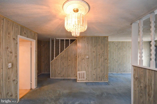 interior space with a notable chandelier, wood walls, and dark colored carpet