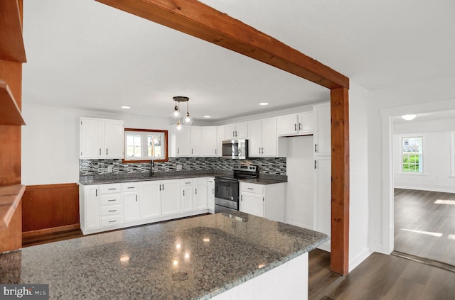 kitchen featuring dark wood-type flooring, dark stone counters, pendant lighting, stainless steel appliances, and white cabinets