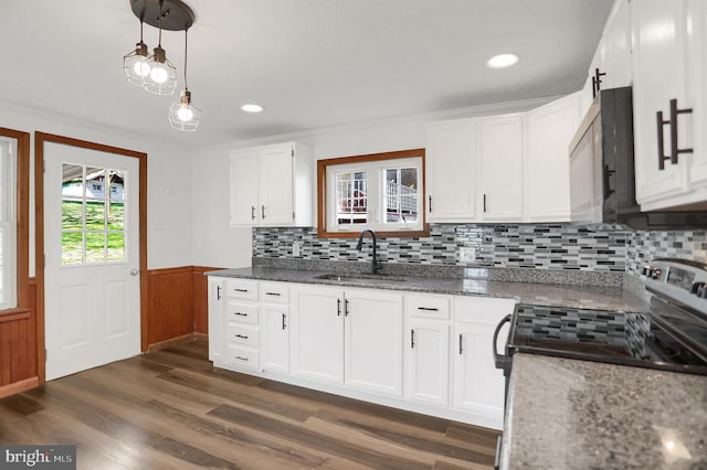 kitchen featuring dark wood-type flooring, sink, decorative light fixtures, electric range, and white cabinets