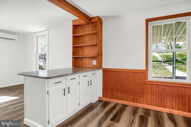 kitchen featuring dark wood-type flooring, dark stone counters, kitchen peninsula, and white cabinets