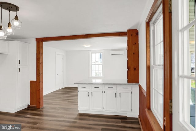 kitchen featuring dark wood-type flooring, white cabinetry, hanging light fixtures, an AC wall unit, and light stone countertops