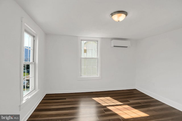 spare room with a healthy amount of sunlight, a wall mounted air conditioner, and dark hardwood / wood-style flooring