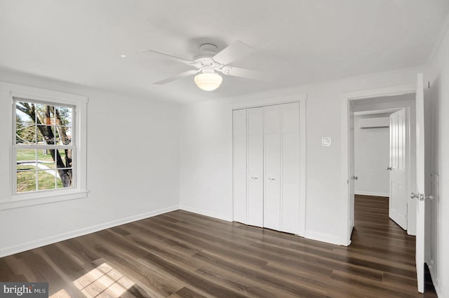 unfurnished bedroom featuring dark wood-type flooring, a wall mounted air conditioner, ceiling fan, and a closet