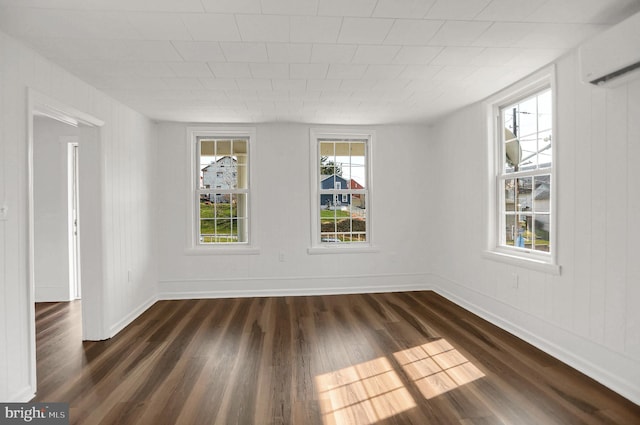 spare room with a wall unit AC and dark hardwood / wood-style floors