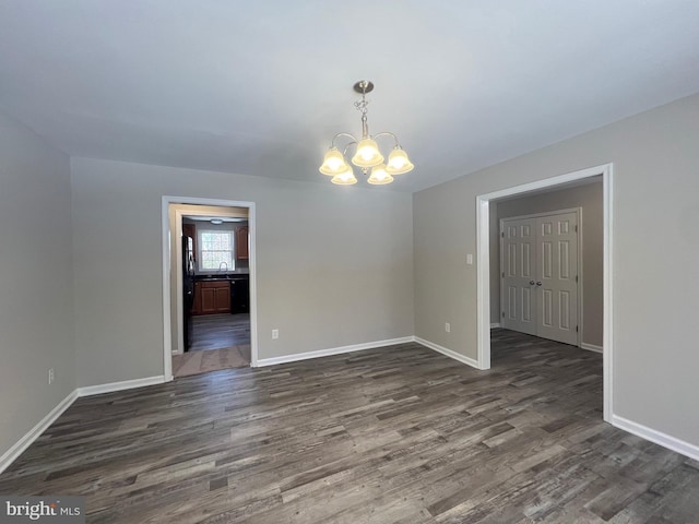 spare room featuring an inviting chandelier, dark hardwood / wood-style flooring, and sink