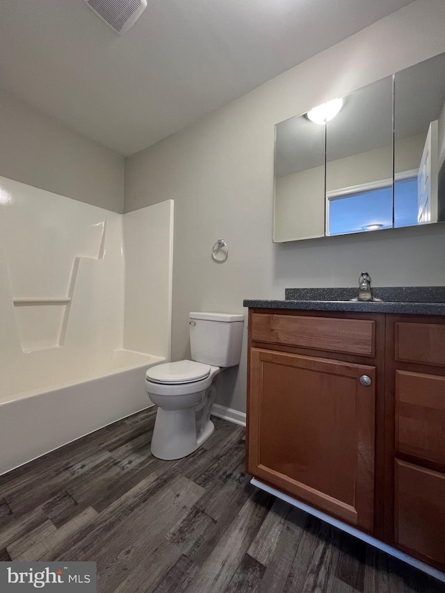 full bathroom featuring toilet, bathing tub / shower combination, hardwood / wood-style floors, and vanity