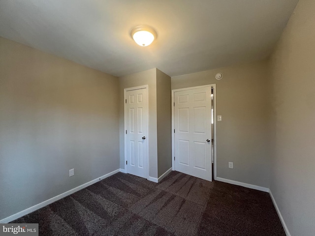 unfurnished bedroom with a closet and dark carpet