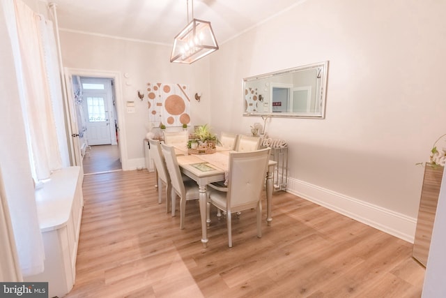 dining room with light wood-type flooring and ornamental molding