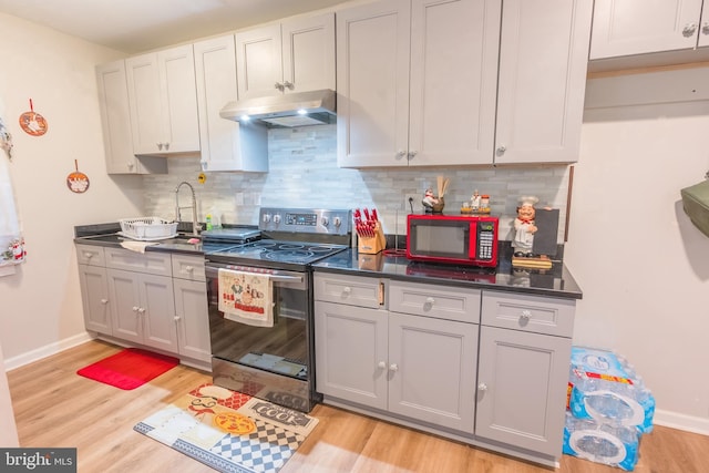 kitchen featuring decorative backsplash, electric range, gray cabinets, and light hardwood / wood-style floors