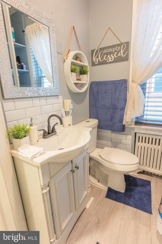 bathroom with radiator, vanity, tasteful backsplash, toilet, and hardwood / wood-style flooring