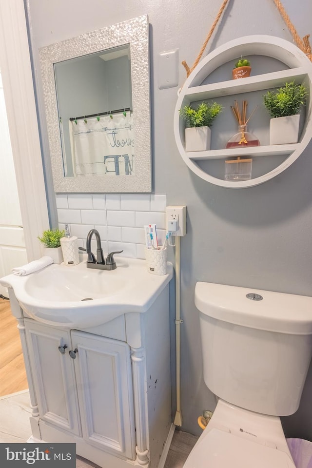 bathroom with tasteful backsplash, vanity, toilet, and hardwood / wood-style floors