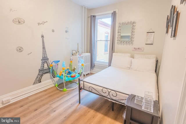 bedroom with wood-type flooring and radiator heating unit