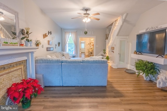 living room with ceiling fan, wood-type flooring, and vaulted ceiling