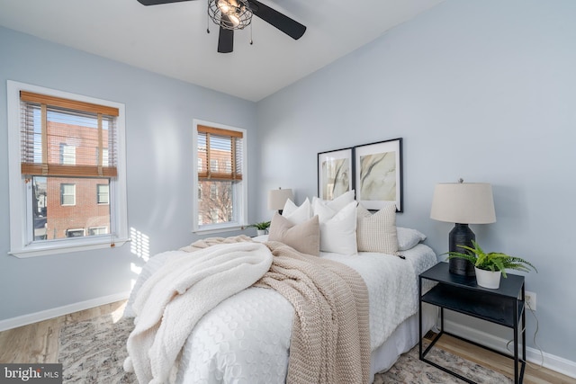 bedroom with ceiling fan, light wood-type flooring, and multiple windows