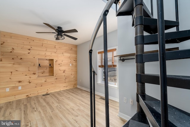 unfurnished bedroom with ceiling fan, light hardwood / wood-style flooring, and wooden walls