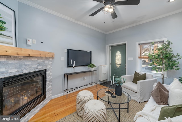 living room with a fireplace, ornamental molding, light hardwood / wood-style floors, and ceiling fan